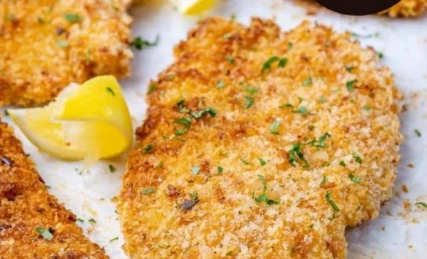Baked Parmesan Crusted Chicken garnished with herbs on a plate