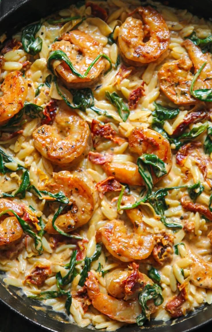 A bowl of creamy Tuscan shrimp orzo with shrimp, sauce, and herbs
