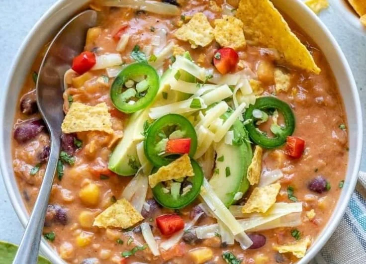 Bowl of Decadent Lentil Tortilla Soup topped with avocado and tortilla strips