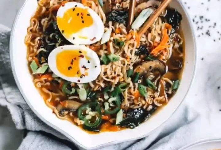 Bowl of homemade healthy ramen topped with vegetables and herbs