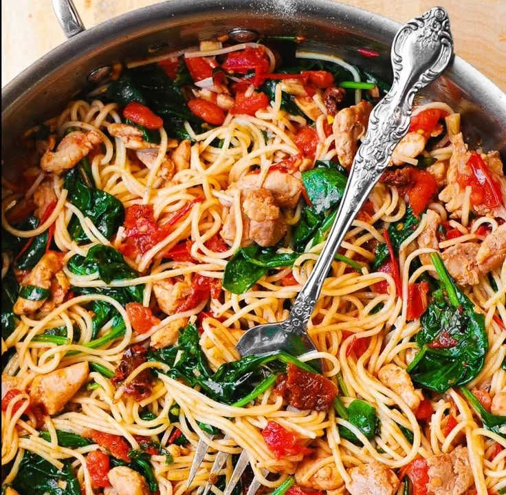 Bowl of Tomato Spinach Chicken Spaghetti garnished with fresh basil